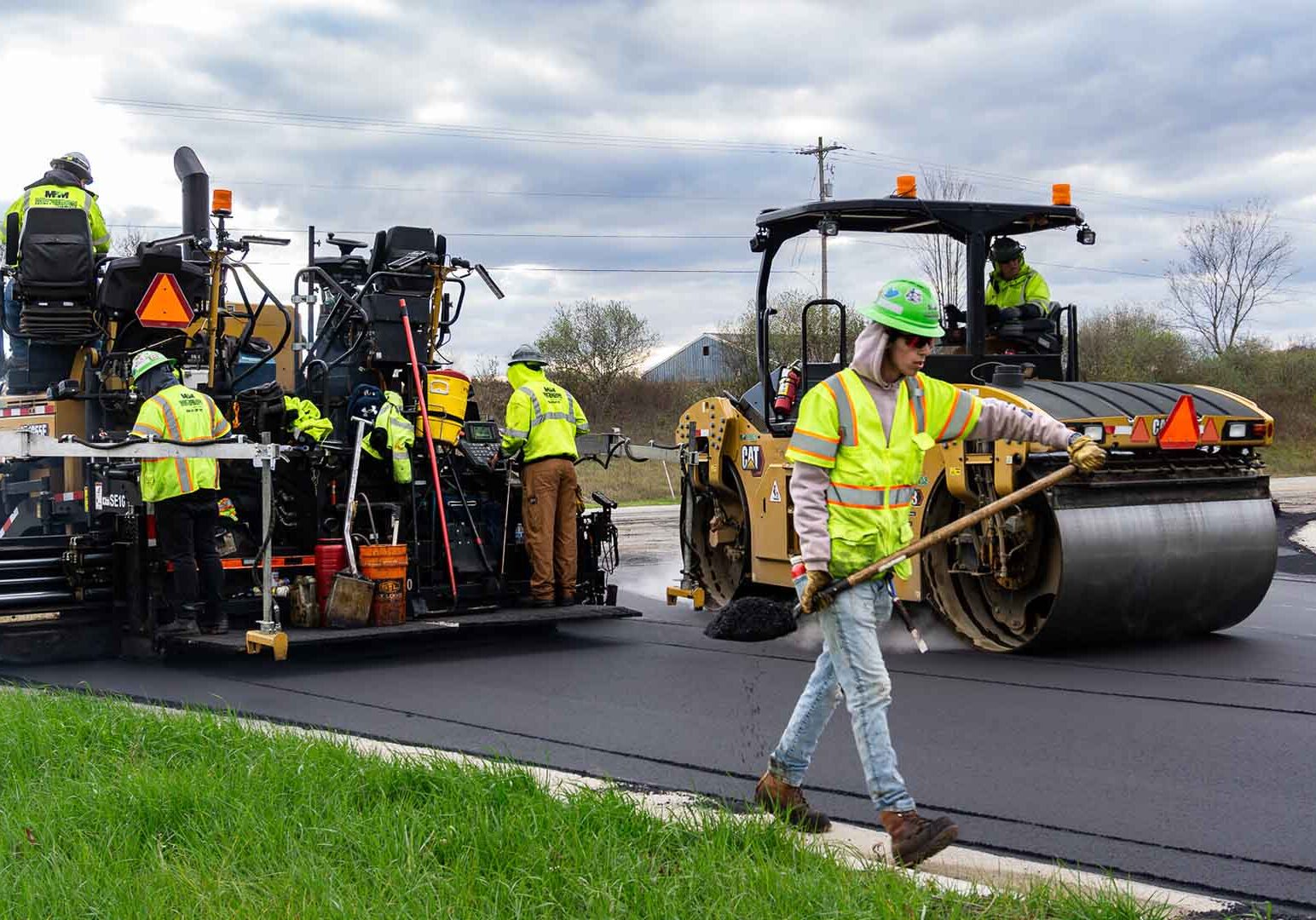 A commercial paving crew laying hot mix asphalt on a large project