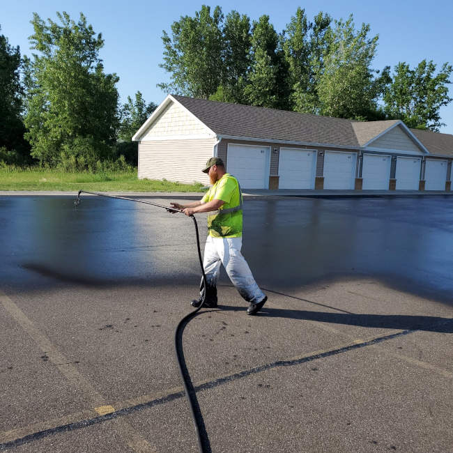 Sealcoating being applied to an asphalt parking lot as part of routine maintenance
